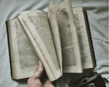 a person is holding a book that is open to a page with a foreign language on it