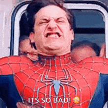 a man in a spiderman costume is making a funny face while sitting in a car .