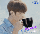 a young man drinking from a black cup with the word ngopi on the bottom