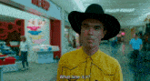 a man wearing a cowboy hat and a yellow shirt asks what time is it