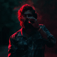 a man with a beard is smoking a cigarette in the dark