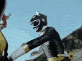a black power ranger is fighting another power ranger in a battle .