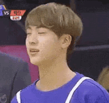a young man in a blue shirt is making a funny face .