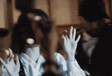 a woman wearing white gloves is waving her hands in front of a man