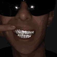 a close up of a man wearing sunglasses and a black shirt with a smile on his face