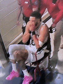 a man in a wheelchair wearing pink shoes is being helped by a man in a red shirt
