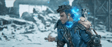 a man with a robotic arm is standing in the snow with blue flames coming out of his chest