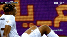 a soccer player is kneeling down in front of a screen that says justaidan