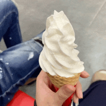 a person is holding a vanilla ice cream cone