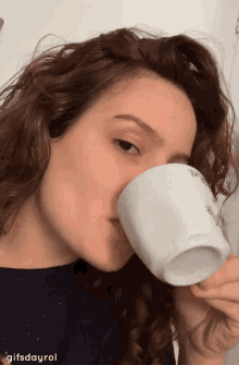 a woman is drinking from a white cup with the gifsdayrol written on the bottom