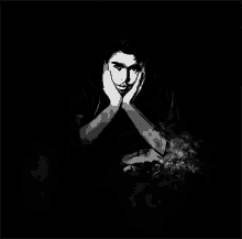 a black and white photo of a man holding his face with his hands