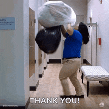 a woman is carrying a large trash bag in a hallway and says thank you .
