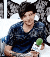 a young man is sitting on a couch holding a microphone .