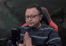 a man wearing glasses prays in front of a microphone