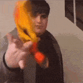 a man with a scarf around his neck is holding a red object in his hand