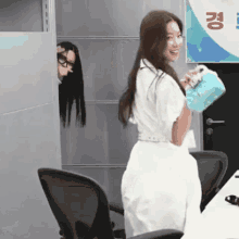 a woman in a white dress holds a blue purse in front of a sign with korean writing