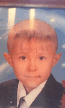 a young boy is wearing a suit and tie and looking at the camera