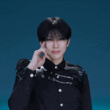 a man in a black shirt is making a heart shape with his hands against a blue background