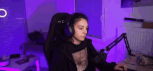 a woman is sitting in a gaming chair wearing headphones and using a computer .