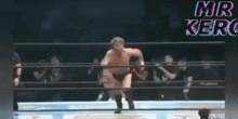a wrestler is jumping in the air in a wrestling ring with the words mr. kerc written above him .