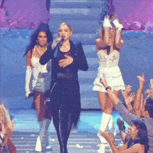a woman is singing into a microphone while two other women are standing behind her