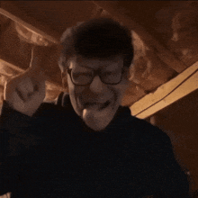 a man wearing glasses is making a funny face in a dark room