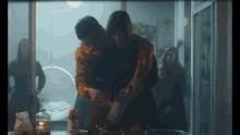 a man and a woman are cooking together and the man is holding the woman 's arm