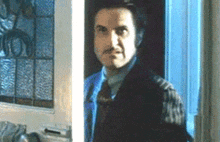 a man in a suit and tie is standing in front of a window .