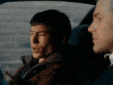 two men are sitting in the back seat of a car and one is looking at his phone