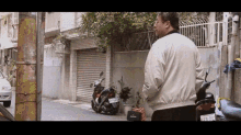 a man in a white jacket is standing next to a motorcycle with a license plate that says ' ec '