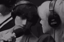 a man and a woman wearing headphones are sitting next to each other in front of a microphone .