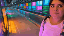 a woman in a white shirt is standing in a hallway with colorful stained glass windows