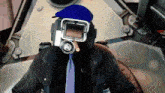 a man wearing a gas mask and a hat has a clock on his wrist