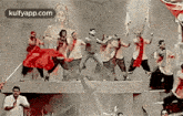 a group of people are dancing in front of a statue .