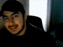 a man with a beard is sitting in a chair and smiling .