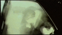 a man in a suit is driving a car with smoke coming out of the window .