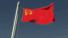 a red flag with yellow letters on it is flying in the wind against a blue sky
