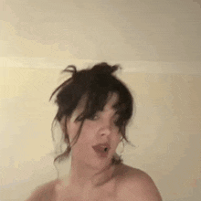 a woman without a shirt is making a funny face .