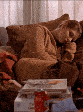 a woman sleeping on a couch next to a can of coke