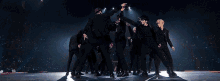 a group of men are dancing on a stage in front of a crowd .