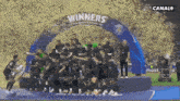 a group of soccer players are standing under a banner that says winners