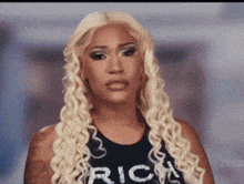 a woman with long blonde hair is wearing a black tank top that says rich