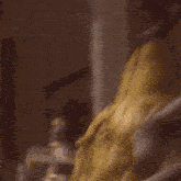 a woman in a yellow dress and wig is standing in front of a window .