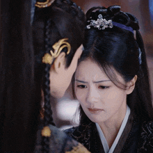 a woman with a purple ribbon in her hair looks at another woman