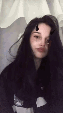 a woman with long black hair and horns on her face