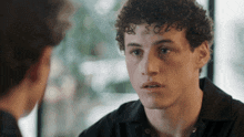 a young man with curly hair has a tattoo on his forehead that says sg26