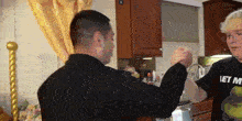 a man wearing a shirt that says " let me " holds another man 's arm