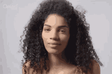 a woman with curly hair is wearing a crowned ladies shirt .