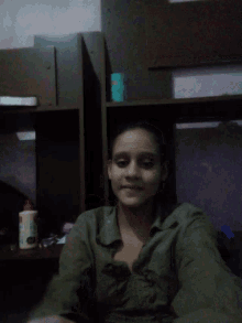 a woman in a green shirt is laying on a bed talking on a cell phone