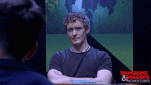 a man sitting at a table with his arms crossed in front of a screen that says dungeons & dragons adventures